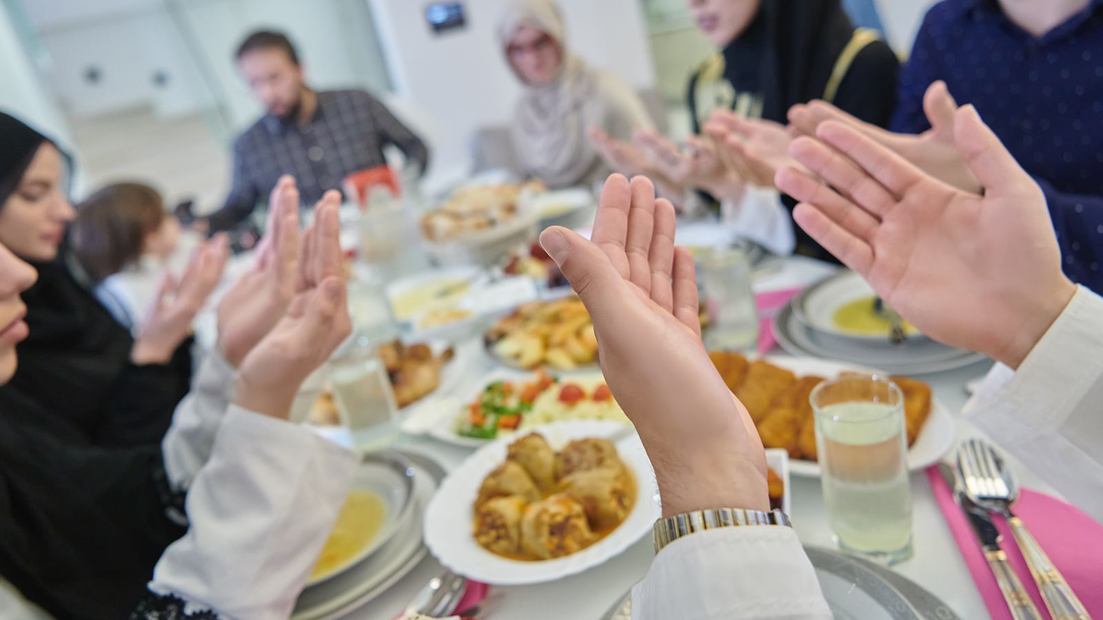 Muslim family making iftar dua to break fasting during Ramadan.
